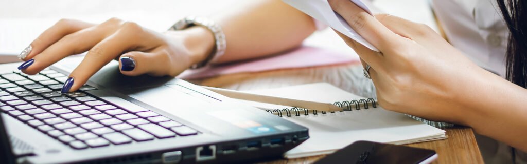 A person's hands interacting with both laptop and paper 