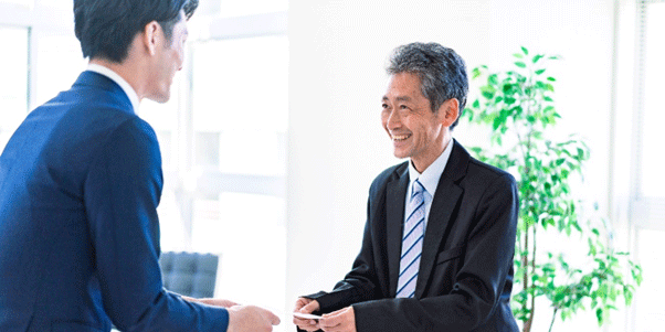 Two businessmen following Japanese etiquette rules for exchanging business cards.