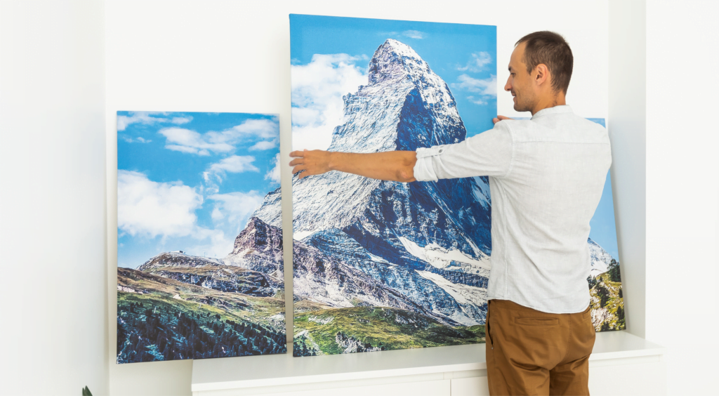 A person setting up canvas prints of a mountain