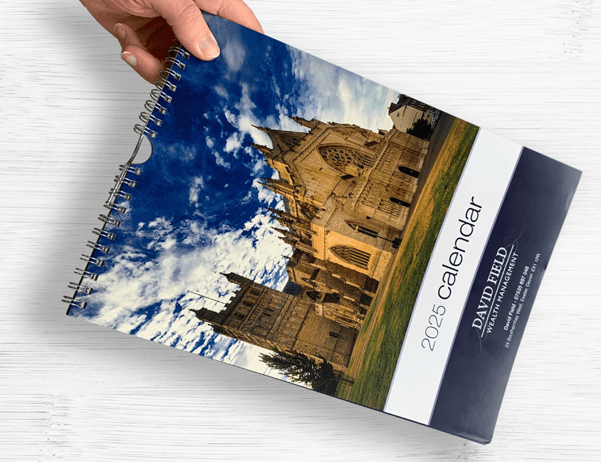 Hand holding a 2025 Calendar over a desk